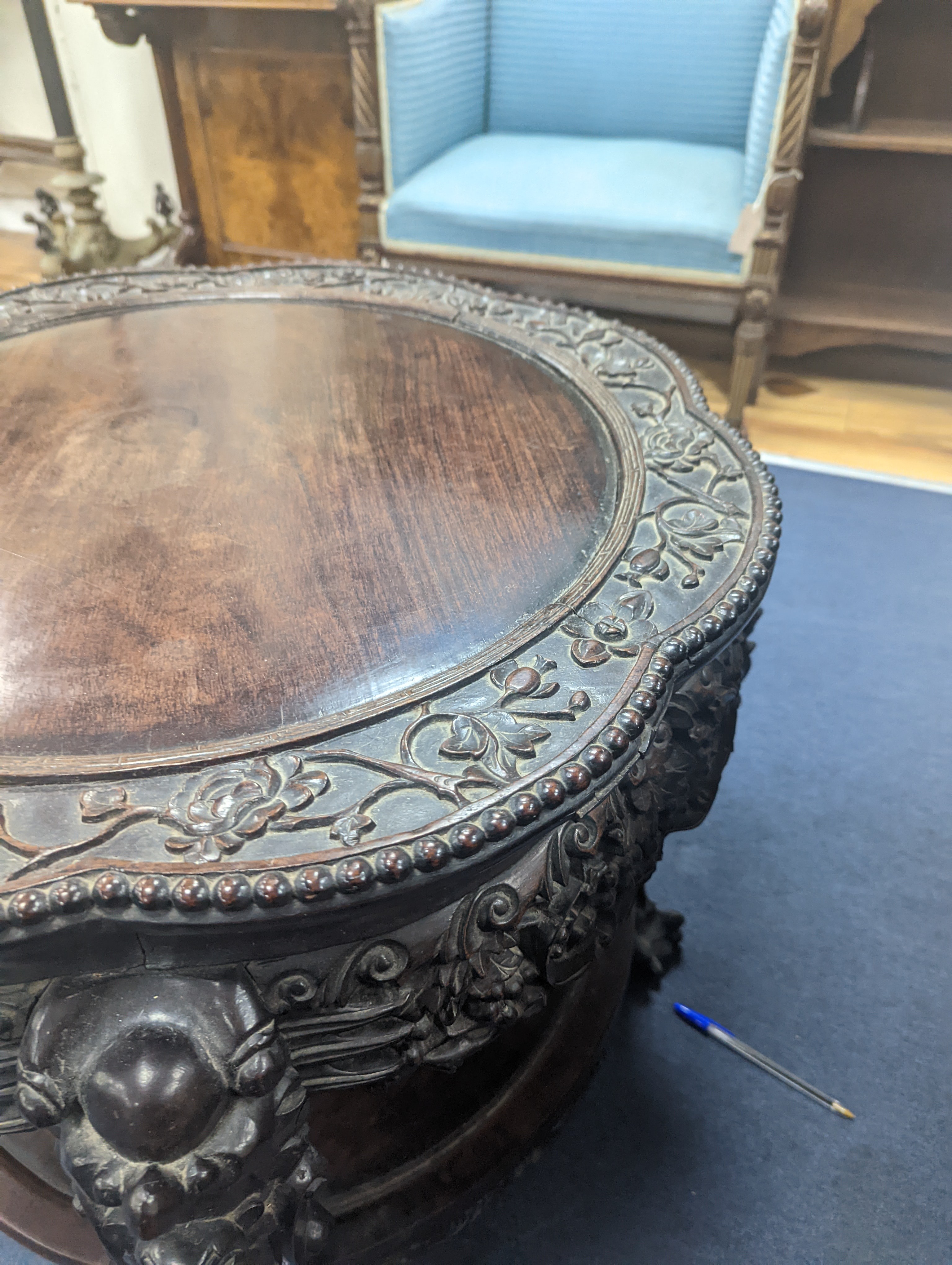 An early 20th century Chinese carved hardwood two tier table, diameter 64cm, height 56cm